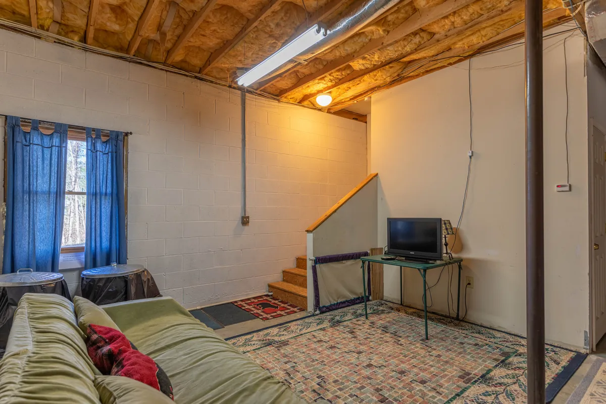 A cozy living area featuring a comfortable sofa, television, stairs, and soft curtains. The layout suggests a social space ideal for relaxing, watching movies, or enjoying quiet group conversations after a day of adventure.